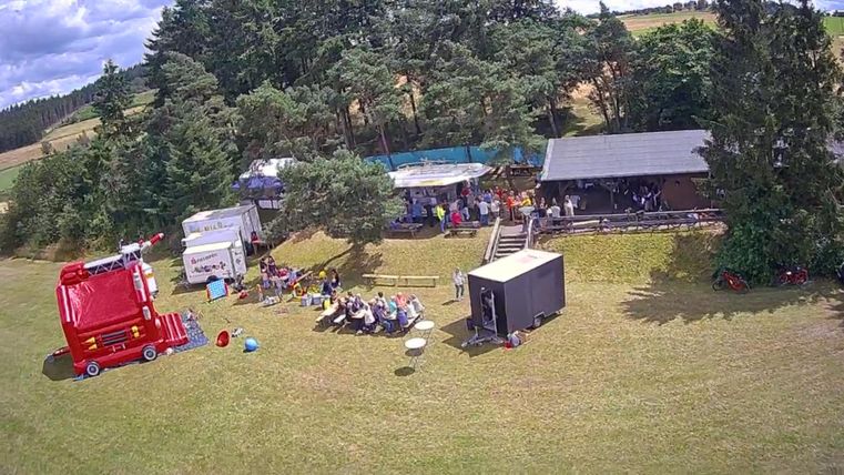 A large meadow with several stalls and a food sales cart. People are gathered in a relaxed atmosphere.
