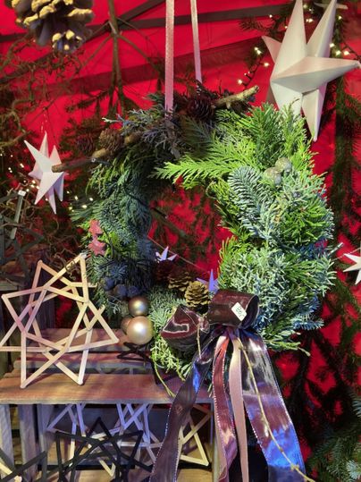 Eine rustikale Dekoration mit Tannenzweigen, roten Kugeln und Tannenzapfen. Sie ist in einem alten Behälter angeordnet und vermittelt ein festliches Gefühl.