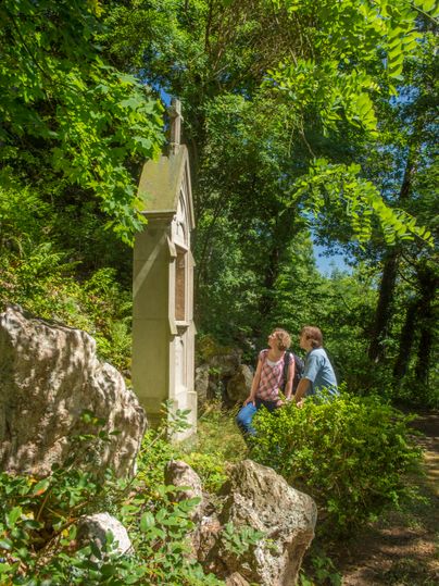 Zwei Personen betrachten ein Denkmal im Wald auf dem Kreuzweg Adenau.