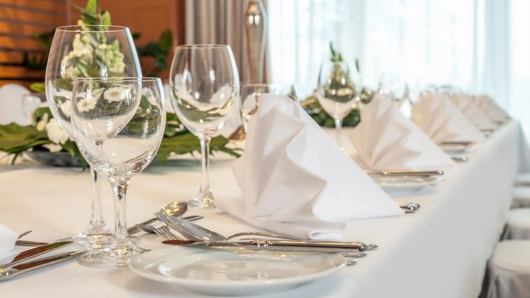 An elegantly set table with glasses, cutlery, and decorative napkins. The atmosphere is festive and inviting.