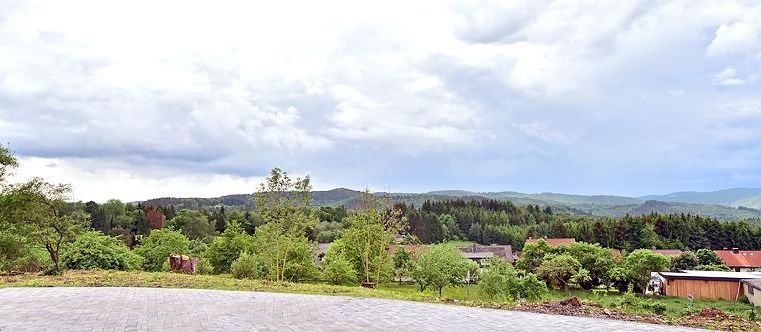 Eine malerische Landschaft mit sanften Hügeln und Bäumen. Der Himmel ist bewölkt und verleiht der Szenerie eine ruhige Atmosphäre.
