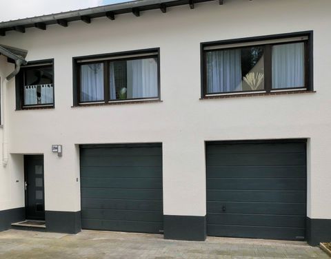 Ein einfaches Gebäude mit zwei Garagentüren und großen Fenstern. Die Fassade ist hell und modern gestaltet.