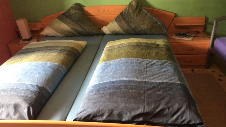 A comfortable double bed with striped pillows. The room has a friendly green wall color.