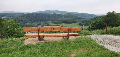 Eine große Holzsitzbank von hinten fotografiert mit Blick auf 