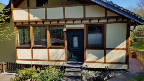 Een charmant huis in vakwerkstijl met een groene ingang. De tuin heeft bloemen en is goed onderhouden.