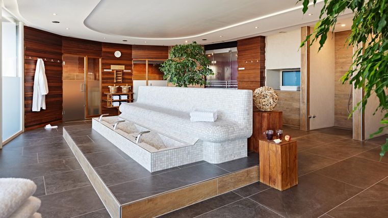 A modern wellness area with a comfortable sofa and plants. The walls are made of wood and the atmosphere is relaxing.