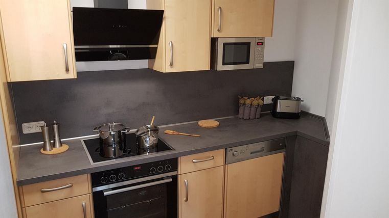 Eine moderne Küche mit Holzmöbeln und Edelstahlgeräten. Die Arbeitsfläche ist grau und gut organisiert.