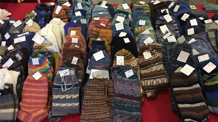 Ein Tisch voller bunter Socken in verschiedenen Mustern und Farben. Die Socken sind beschriftet und ordentlich angeordnet.