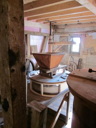 A traditional mill with wooden structures and machines for grinding. The interior is rustic and showcases craft details.