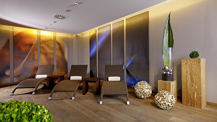 A modern relaxation area with loungers and soft lighting. The walls are decorated with calming images, and there are plants in the room.