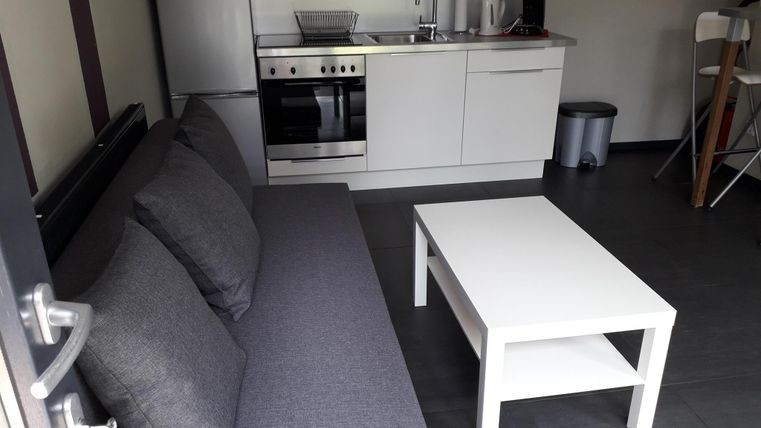 Eine moderne Küchenzeile mit einem grauen Sofa und einem weißen Couchtisch. Der Raum wirkt hell und einladend.