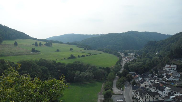 Eine malerische Landschaft mit sanften Hügeln und einem kleinen Fluss. Im Vordergrund ist ein beschauliches Dorf zu sehen.