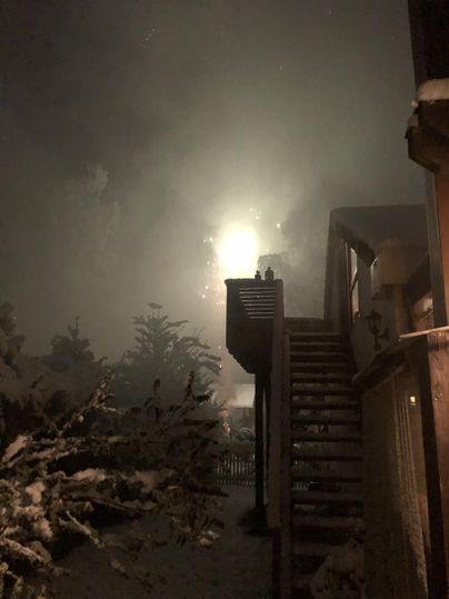 A wintry night scene with a illuminated building and a staircase. The sky is foggy and mysterious.
