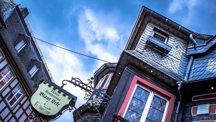 A picturesque restaurant named "Blue Corner" in a historic building. The sky is overcast, creating a moody atmosphere.