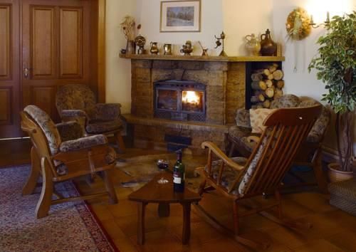 Een gezellige woonkamer met een open haard waar een vuur brandt. Comfortabele stoelen en een kleine tafel met een fles wijn creëren een uitnodigende sfeer.