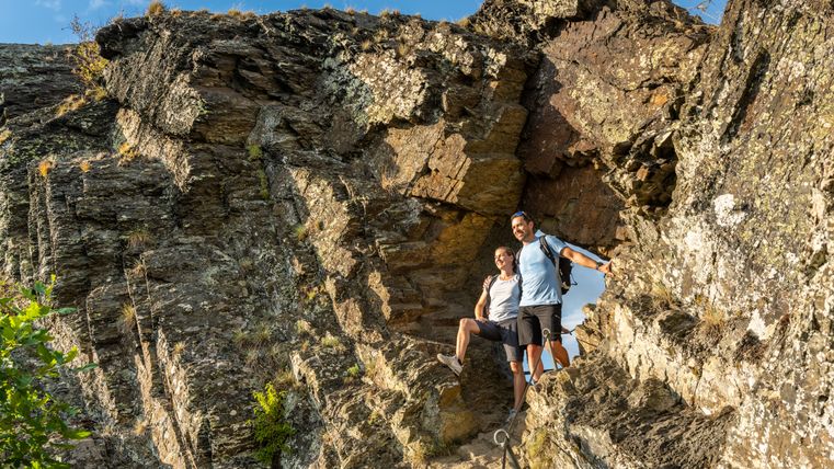Felsen mit einem Loch in dem eine Frau und ein Mann stehen in Wanderausrüstung