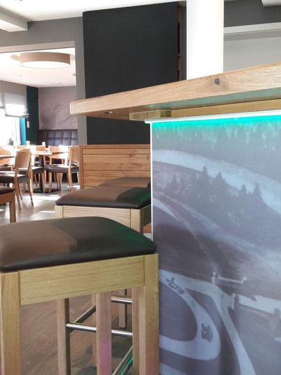 A modern restaurant with wooden stools and bar chairs. The atmosphere is bright and inviting.