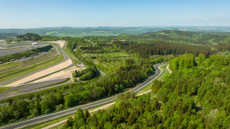Luftaufnahme des Nürburgrings mit umliegenden Wäldern und Rennstrecke.