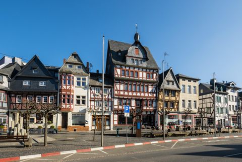 A picturesque old town with historic half-timbered houses. The sky is clear and the street is quiet.