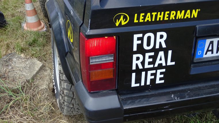 Ein schwarzes Auto mit einem auffälligen Aufkleber, der die Worte „FOR REAL LIFE“ zeigt. Das Logo von Leatherman ist ebenfalls gut sichtbar.