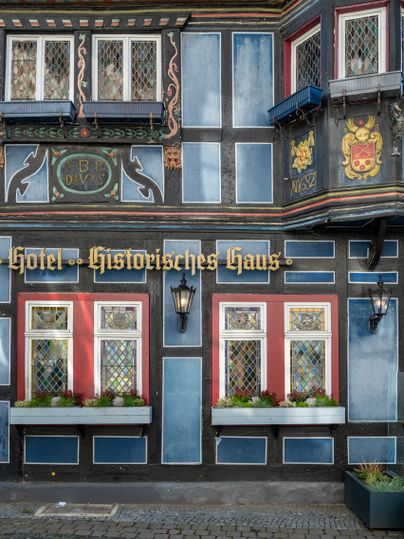 Fassade eines historischen Fachwerkhauses mit dekorativen Fenstern und Pflanzenkästen in Adenau.