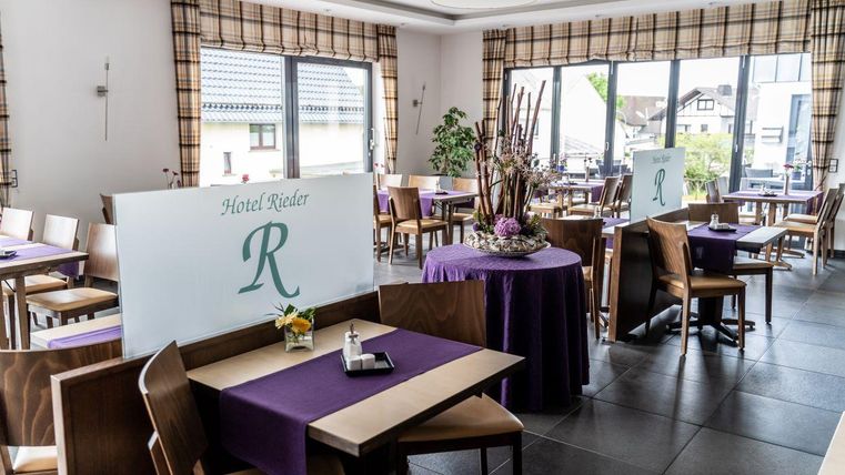 Een uitnodigend restaurant met elegante tafels en stoelen. De ramen bieden een mooi uitzicht naar buiten en de decoratie zorgt voor een aangename sfeer.