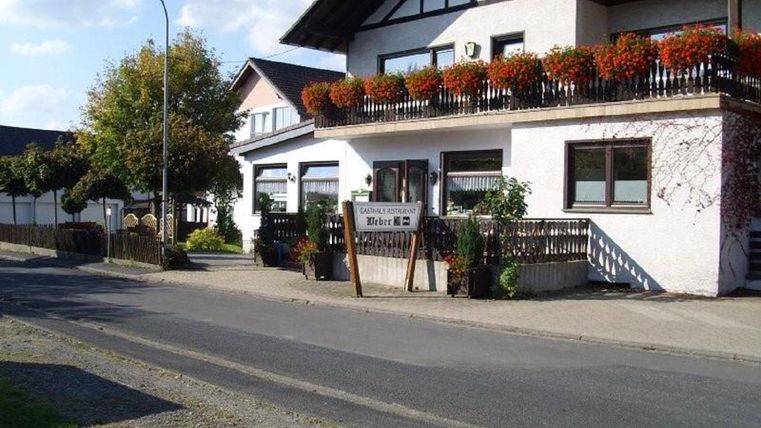 Ein charmantes Gebäude mit einem Balkon voller Blumen. Neben der Straße steht ein Hinweis auf eine Unterkunft.