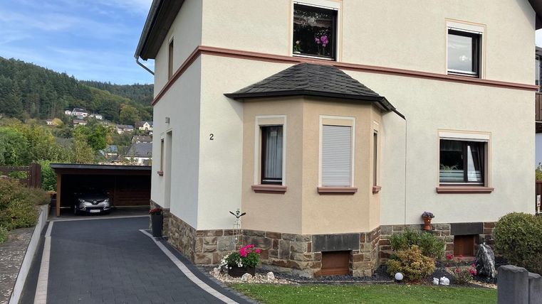 Une belle maison avec un chemin pavé et une place de garage. L'environnement est vert et soigné.