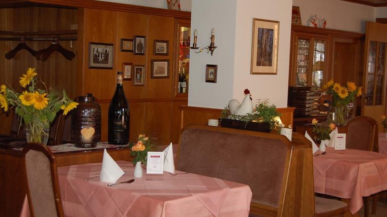 Een gezellig restaurant met houten meubels en bloemstukken op de tafels. De sfeer is uitnodigend en vriendelijk.