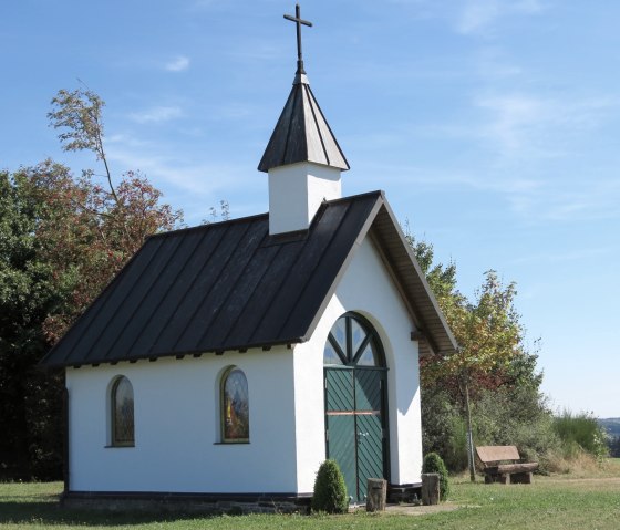 The Kottenborn Chapel in Wershofen stands in a meadow surrounded by trees. It has a green gate and a cross on the roof., &copy; TI Hocheifel N&uuml;rburgring