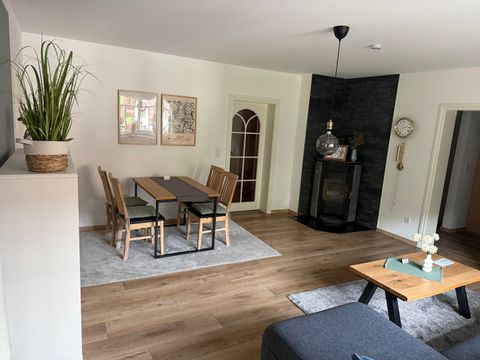 Een moderne woonkamer met een eetgedeelte en een aangename lichtsfeer. De ruimte is ingericht met een houten vloer en een gezellige zithoek.