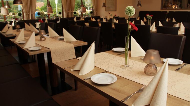 Ein stilvolles Restaurant mit gedeckten Tischen und eleganten Servietten. Die Atmosphäre ist warm und einladend.