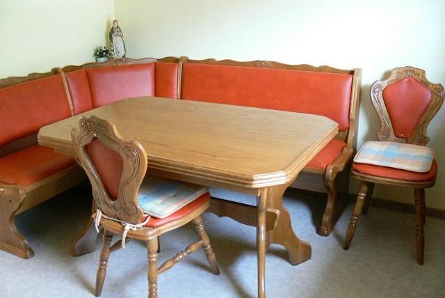 Een gezellige eetruimte met een houten tafel en rode stoelen. De inrichting heeft een rustieke charme en een uitnodigende sfeer.