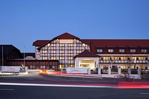 A modern hotel building with traditional architecture. The facade is brightly lit in the evening light.