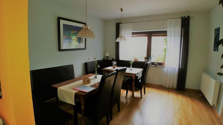 A cozy dining area with four chairs and a table. Large windows let in plenty of daylight and give the room an inviting atmosphere.