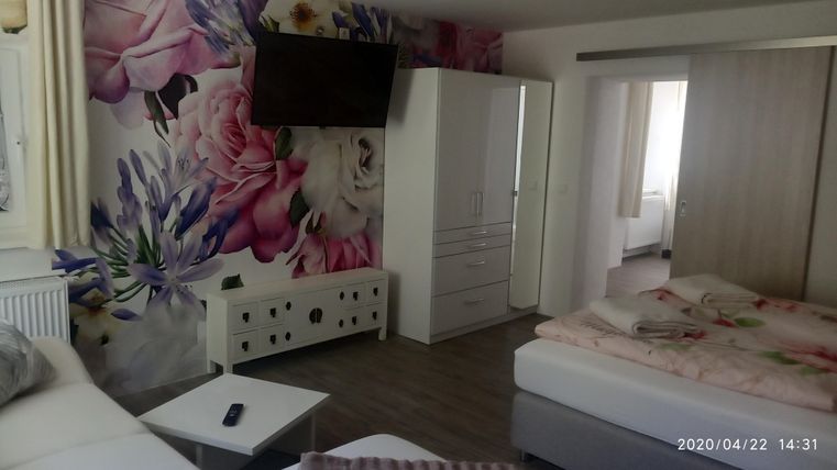 A modern room with a large TV and floral wallpapers. There is a comfortable bed and a bright, inviting atmosphere.