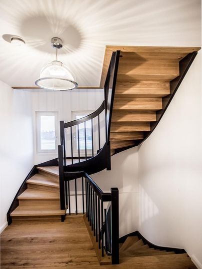 Eine elegante Treppe aus Holz und Metall in einem modernen Innenraum. Die Wände sind weiß und der Raum ist hell erleuchtet.