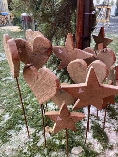 Eine weihnachtliche Dekoration mit einer roten Kugel, goldenen Sternen und roten Beeren. Schnee bedeckt die oberste Schicht, was eine festliche Stimmung vermittelt.