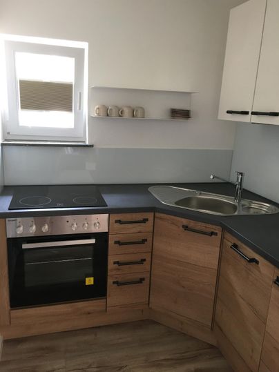 Une cuisine moderne avec des armoires en bois et une combinaison de cuisinière et d'évier. La fenêtre apporte de la lumière naturelle dans la pièce.