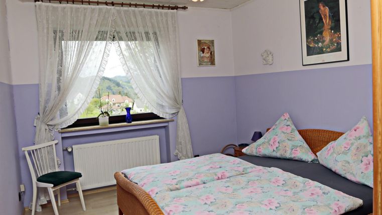 Een gezellige slaapkamer met een tweepersoonsbed en kleurrijke dekens. Het raam biedt uitzicht op het landschap en is versierd met gordijnen.