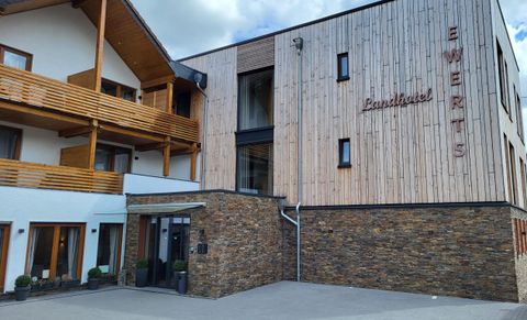 A modern country hotel with a wooden facade and large windows. The entrance area is designed to be welcoming and encourages visitors to linger.