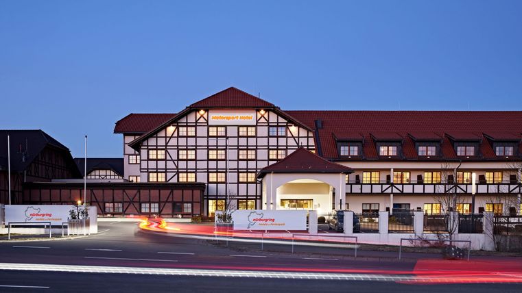 Een modern hotelgebouw met traditionele architectuur. De gevel is kleurrijk verlicht in het avondlicht.