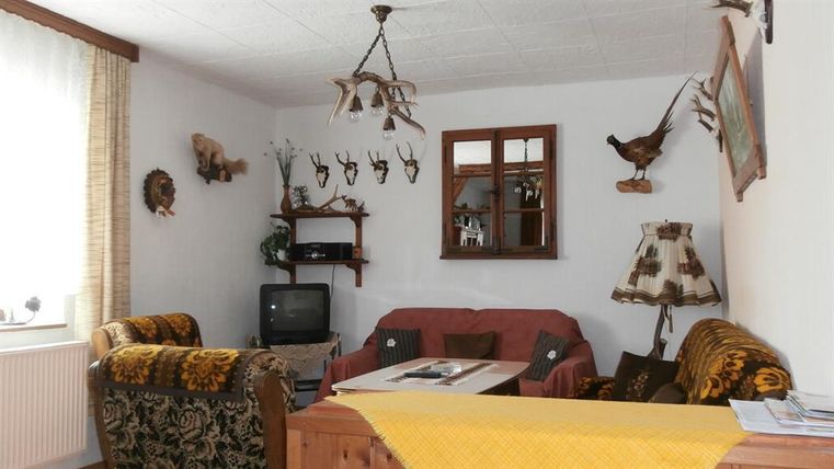 A cozy living space with two sofas and a table in the middle. Decorations and hunting trophies hang on the walls.