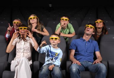 Eine Gruppe von Menschen sitzt im Kino und trägt 3D-Brillen. Sie zeigen verschiedene Gesichtsausdrücke und scheinen den Film zu genießen.
