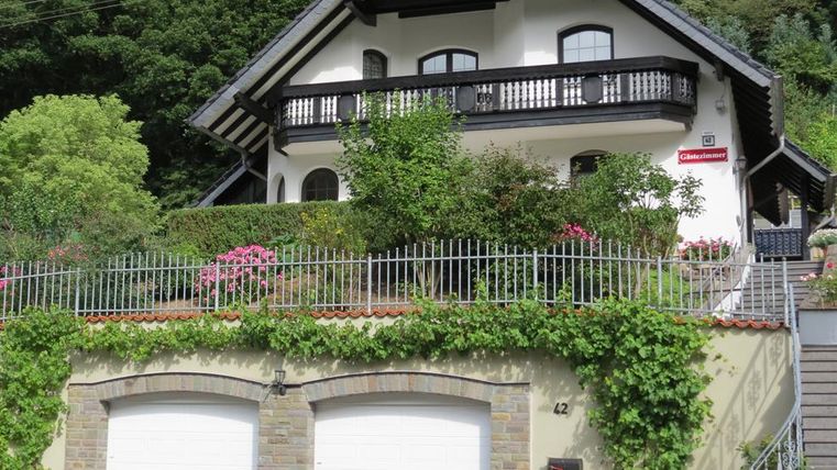 A lovely house with a balcony and a well-maintained garden.
In front of the house are two garage doors and a quiet seating area.