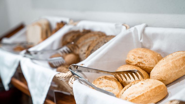 Een buffet met verschillende soorten brood in manden. De verse broodjes en broden zijn op een witte doek gepresenteerd.