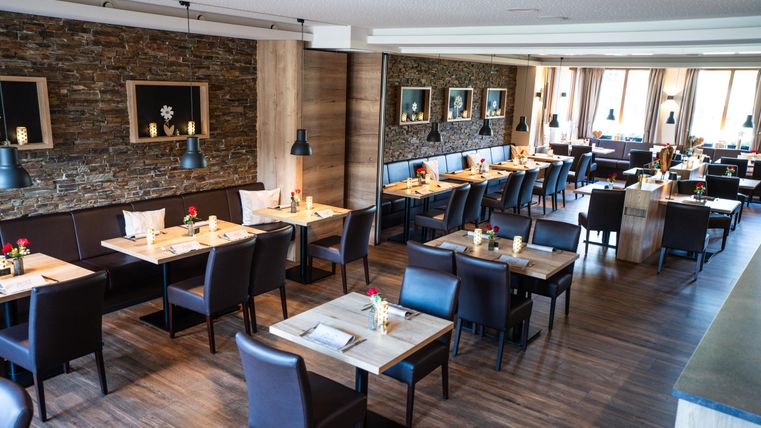 Een elegant restaurant met houten vloeren en moderne meubels. Tafels zijn versierd met bloemen en de muren zijn versierd met kunstwerken.