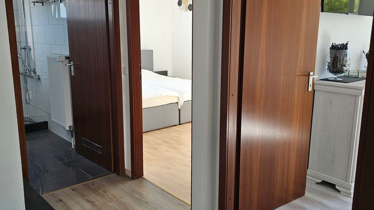 A bright corridor with two open doors leading to different rooms. The floor is made of wood and the walls are painted in neutral colors.