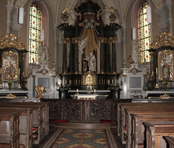 Pr&auml;chtiger Kircheninnenraum mit kunstvollem Altar, h&ouml;lzernen B&auml;nken und bunten Glasfenstern., &copy; Eifel Tourismus GmbH
