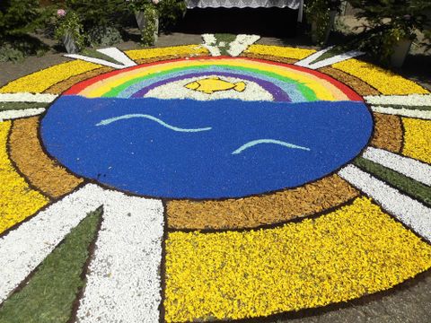 Een kleurrijke bloemmotief toont een zon boven een blauw water met een regenboog. Het ontwerp is levendig en straalt vreugde uit.